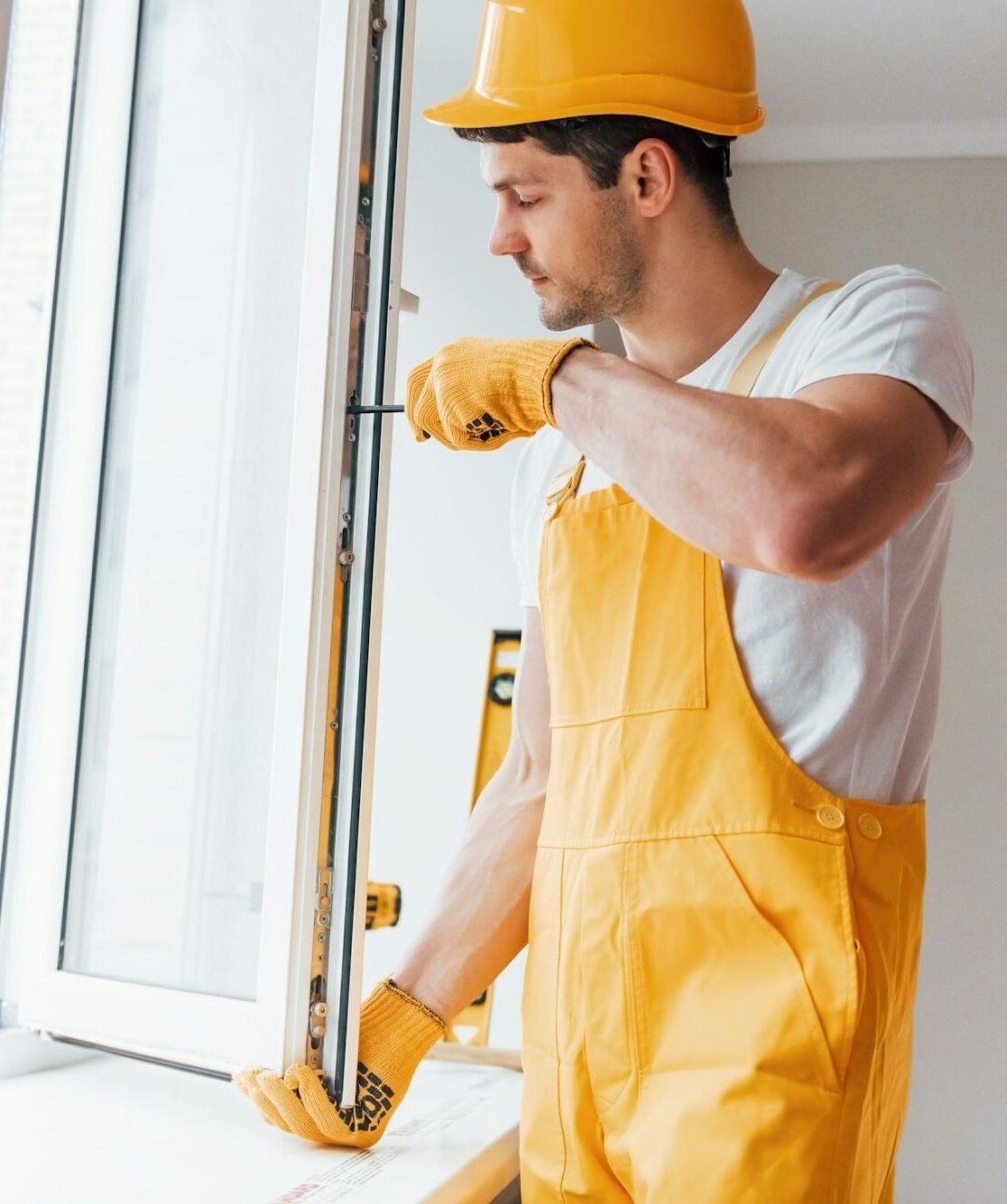 handyman in yellow uniform installs new window house renovation conception e1721899289556